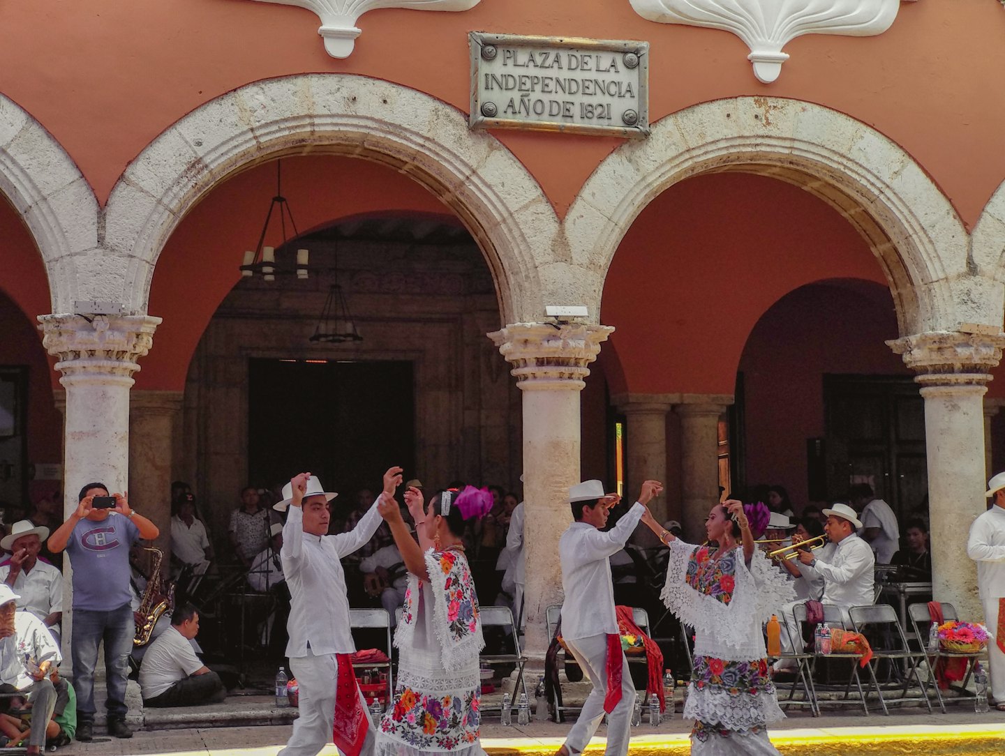 Bailarines actúan al aire libre frente a un edificio con arcos.